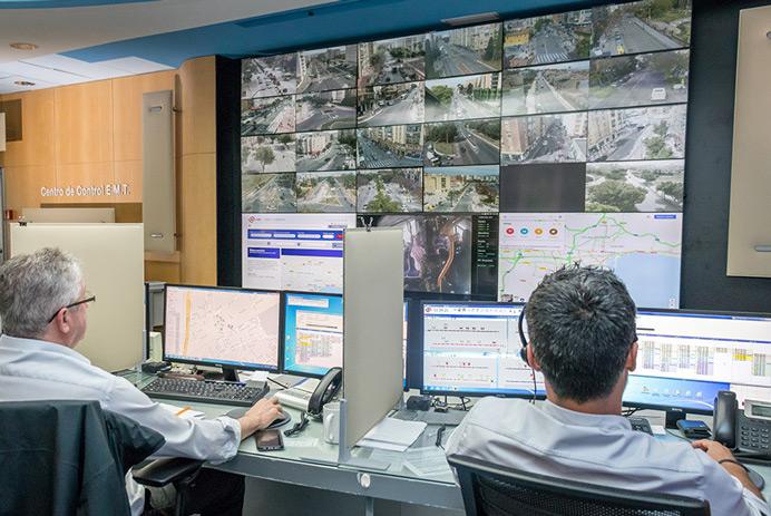  EMT Madrid Kontrollraum mit zwei Mitarbeitern, die die Straßen überwachen und Daten auf einer Videowand anzeigen