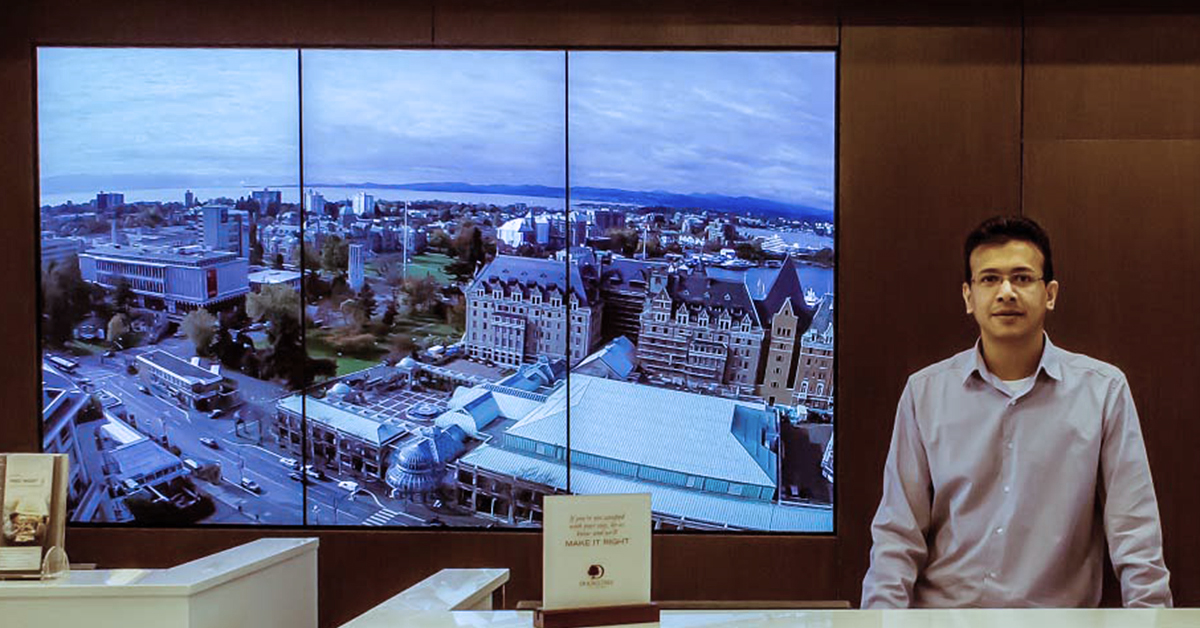DoubleTree by Hilton-Rezeptionist und 3-Panel-Videowand hinter ihm, die Wahrzeichen von Victoria, Kanada, zeigt