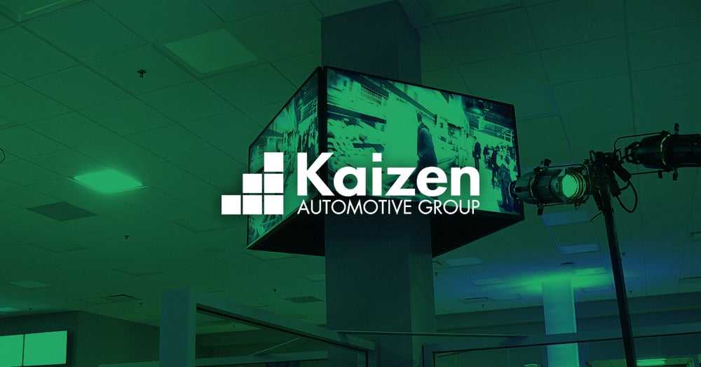 Videowand mit Autowerbung in einem Autohaus der Kaizen Automotive Group mit grünem Overlay und Logo