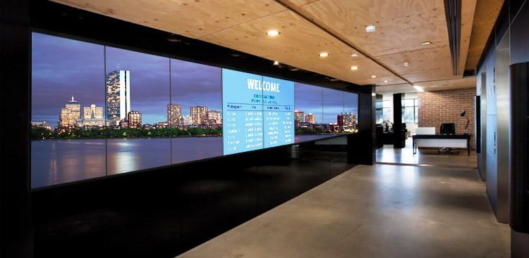 Leere Bürolobby mit einer großen Videowand, auf der ein Willkommensbanner und ein Foto der Stadtsilhouette zu sehen sind