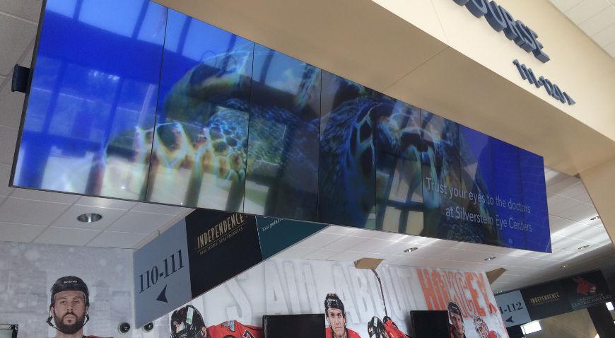 Hängende Videowand in einem Einkaufszentrum, die eine Werbung für Silverstein Eye Centers zeigt