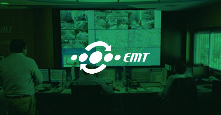 EMT-Mitarbeiter, die den Transitbetrieb an ihren Arbeitsplätzen und auf einer Videowand überwachen, auf der Live-Kamerabilder, Transitkarten und Websites mit grünem Overlay und Logo angezeigt werden