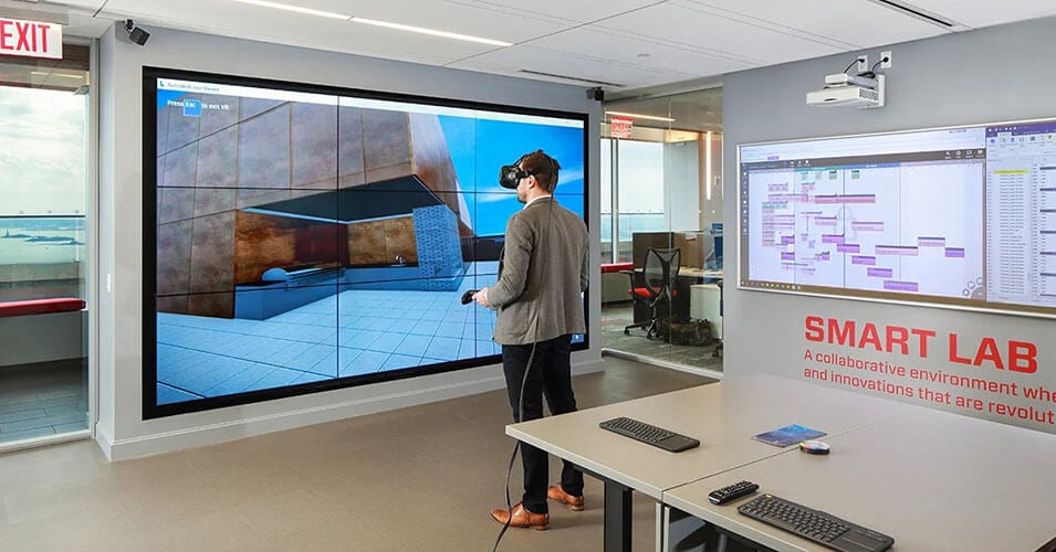 Der Smart-Lab-Raum in Suffolk mit einem Schreibtisch und einem Mann, der die virtuelle Realität erkundet, und einer Videowand, die das virtuell Gesehene zeigt